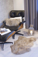 Modern black leather armchair with a fur throw and candle in a room with gray curtains.