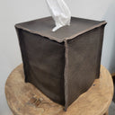 Brown leather tissue box cover with a white tissue on a wooden surface