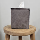 Gray textured tissue box on a wooden stool against a light gray background
