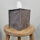 Gray fabric tissue box cover on a wooden stool with a neutral background