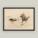 Framed artwork of a cowboy on horseback chasing a steer with a lasso.