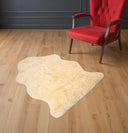 cream sheepskin rug on a wooden floor with a red chair in the background.