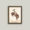 Framed vintage western art print of a rodeo cowboy riding a bucking bronco, in a dark wood frame.