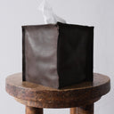 Dark brown leather tissue box cover on wood stool in front of white background
