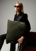 Woman holding a textured green pillow against a neutral background