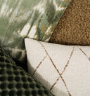 Close-up of various textured pillows including a green patterned, brown textured, and beige geometric pillow.