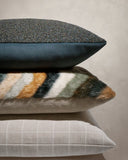 Stack of three textured pillows on a neutral background