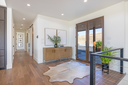 Modern entryway with a natural wood sideboard, cowhide rug, framed wall art, and large windows in a bright open home interior.