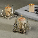 Decorative candle holders with candles on a textured surface with a book in the background.