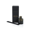Aromatherapy diffuser set with black packaging and black and amber glass vessel on a white background