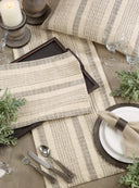 Elegant table setting with striped placemats, silverware, and greenery.