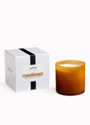 A LAFCO New York candle in an amber glass jar next to its white packaging box with a black ribbon, on a clean white background.