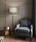 Gray armchair with a lamp and side table in a room with paneled walls.