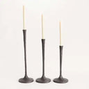 Three dark metal candle holders with candles on a white background