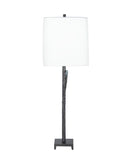 A side view picture of a table lamp with a tall white drum shade and a dark, textured branch-like metal base on a solid white background.