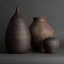 Three dark brown ceramic vases of varying sizes on a gray background