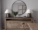 Wooden sideboard with lamps, mirror, and decor against a gray wall.