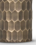 Close-up of a cylindrical product with a textured honeycomb pattern in metallic bronze and brown tones against a white background.