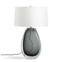 Table lamp with a white shade and a dark glass base on a white background