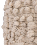 Close-up of a chunky woven textile with raised pom-pom loops in a warm off-white or cream tone against a white background.