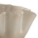 A close-up of a translucent beige glass vessel with a wavy, scalloped rim and smooth glossy finish, set against a plain white background.