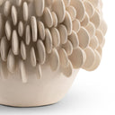 A close-up of a sculptural ceramic vase with a textured, organic pattern of raised petal-like shapes on a plain white background.
