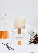 LAFCO White Maple Bourbon scneted candle in a white speckled glass vessel with warm amber accents sitting on a white and gold confetti box  