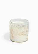 White glass candle with warm gold and brown streaks and white wax with a white background
