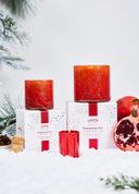 LAFCO Pomegranate Fizz scented candle in a vibrant red glass vessel with subtle gold marbling.  Sitting on top of the white, red confetti boxes with pomegranate, clove and evergreen accents 