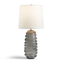 Table lamp with textured gray glass 
base and white shade on a white background