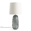 Table lamp with textured gray glass base and white shade on a white background