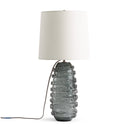 Table lamp with textured gray glass base and white shade on a white background