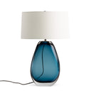 Table lamp with blue glass base and white lampshade on a white background