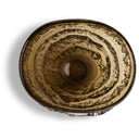A top-down view of a round, smoky amber glass bowl with concentric textured rings and a ribbed base, set against a plain white background.