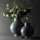 Two dark blue vases with a bouquet of white flowers on a dark background
