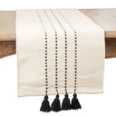 An off-white woven table runner with black vertical dotted stripes and four black tassels at the bottom
