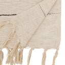 Close up of Cream woven table runner with thin black stripes and tasseled fringe