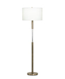 A modern floor lamp with a white drum shade, a brushed brass-finished metal stand, and a clear cylindrical glass accent in the center, set against a plain white background.