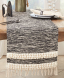 Black and cream woven table runner with textured stripe detailing and fringed ends, styled on a rustic wood dining table