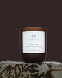 dark amber candle with a white label on a textured surface