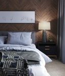 Wyatt grey table lamp with white drum shade styled on a nightstand in a moody bedroom setting,